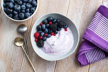 Berry yogurt with fresh berries topping on a wooden table background, top view. Clean eating