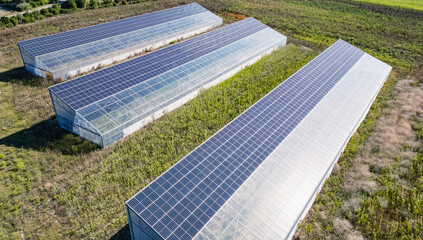Aerial view of modern solar greenhouses with photovoltaic panels on roofs, renewable energy and sustainable farming concept