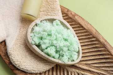 Wooden plate with natural body scrub and massage glove on green background, closeup