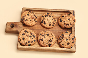 Wooden board of sweet cookies with chocolate chips on yellow background