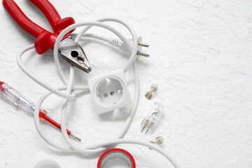 Electrician's tools, extension cord and electronics on white grunge background