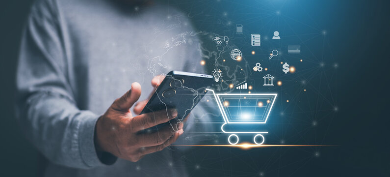 Digital shopping concept with a hand holding smartphone and virtual cart icons. Representing global e-commerce. Online payment. Digital marketing and mobile technology in modern business.