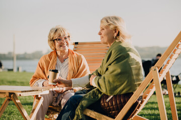 Two senior women enjoying coffee and conversation outdoors