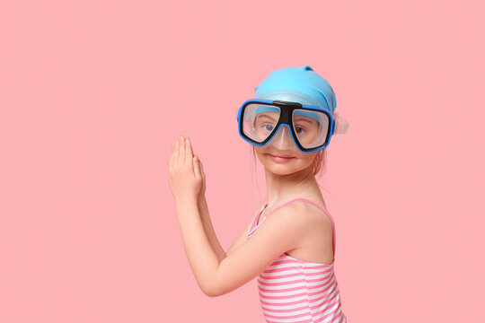 Cute little girl in swimsuit with swimming hat and snorkeling mask preparing to jump into water on pink background - Powered by Adobe