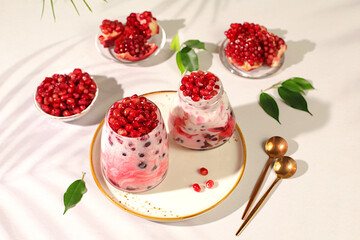 Glasses with pomegranate yogurt with pomegranate pieces, raisins with fresh cream for healthy eating. Healthy breakfast with ingredients, kitchen background, Natural nutrition and diet concept, menu