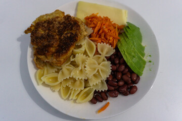 Delicious plate of pasta vegetables and fried chicken served in a home kitchen setting