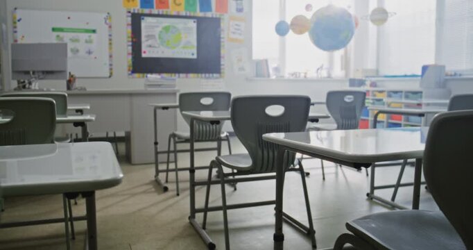 Interior of Modern Empty Primary School Classroom with Desks for Students, Chalkboard, Hanging Models of Solar System and Colorful Posters. Creative Space for Children Studying and Education Process.