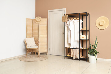 White door, folding screen and shelving unit near beige wall in interior of modern hall