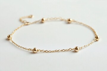 Fototapeta premium Minimalist golden charm bracelet with small beads resting on a white background, representing elegance and simplicity in jewelry design