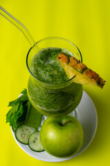 Healthy green detox smoothie with fresh ingredients like apple, pineapple, and cucumber, a...