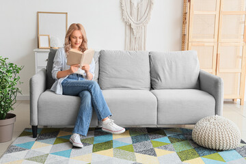 Obraz premium Beautiful blonde woman reading book on sofa at home