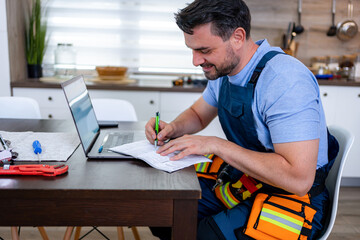 Handyman completing household repair documentation at modern kitchen table