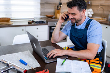 Handyman working from home on heating repair while talking on phone at kitchen table