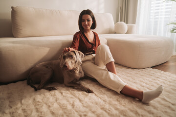 A Cozy Indoor Scene Depicting a Woman and Her Dog Comfortably Relaxing on a Plush Rug