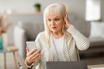 Oh No. Portrait of shocked frustrated middle-aged woman having problems, holding and looking at...