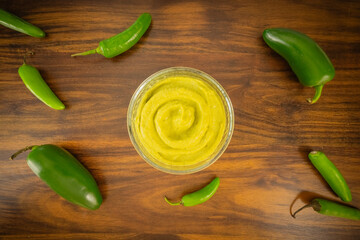 Mexican homemade spicy guacamole sauce in glass bowl with ingredients in wooden surface, topview flat lay with copy space