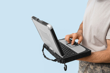 Young soldier working with military laptop on light background, closeup