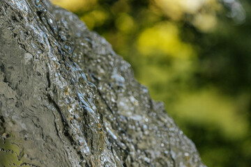 Close-up of water cascading downward, capturing crisp droplets and fluid textures against a soft green background.