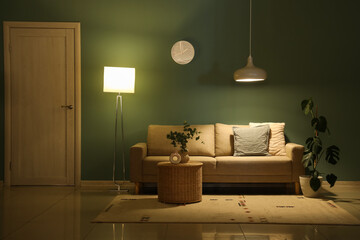Interior of dark living room with sofa, basket and glowing lamps at night