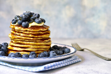 Stack of fresh hot banana pancakes with maple syrup and blueberries for a breakfast.