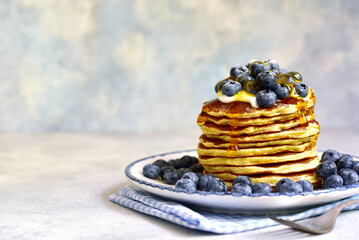 Stack of fresh hot banana pancakes with maple syrup and blueberries for a breakfast.