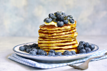 Stack of fresh hot banana pancakes with maple syrup and blueberries for a breakfast.