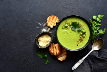 Green pea soup with parmesan and croutons . Top vie with copy space.