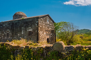 Historic stone building with dome roof in a rural landscape. Surrounded by old stone walls. Timeless architecture and cultural heritage under a clear blue sky. Church on Yason Burnu in Ordu, Turkey.
