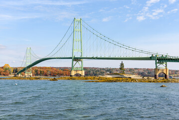 View of a steel supension road bridge over a strait on a clear autumn day 