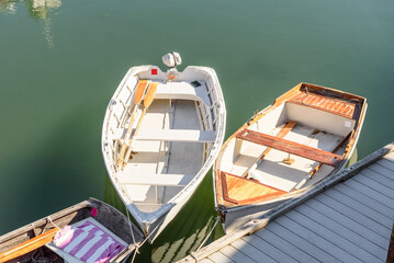 Empty dinghies moored to a jetty in a harbour on a sunny autumn day