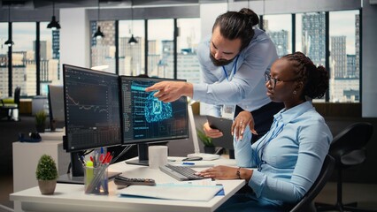 Fototapeta premium Teamworking proprietary firm colleagues using deep learning to assess stock market volatility. Brokerage company supervisor and african american woman using AI to generate investment reports