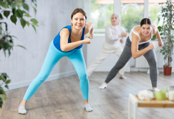 Obraz premium Adult woman in sportswear performs fitness exercises in fitness center
