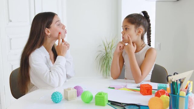 Speech therapist guides child through articulation exercises at therapy session in bright, modern office