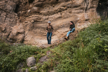 Mother and daughter dressed in hiking clothes, walking along a trail in the middle of the...