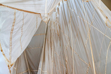 Large white and brown kite with symmetrical pattern, folded or suspended, against a minimalistic...