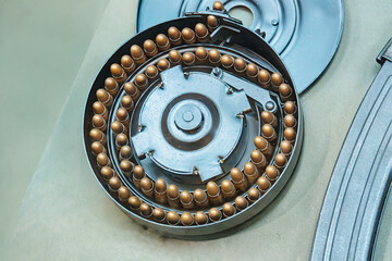 Close-up view of a brasscopper alloy mechanical object with cylindrical components in a circular pattern, possibly part of machinery or wheel Indoor setting, realistic style, no text or people visi