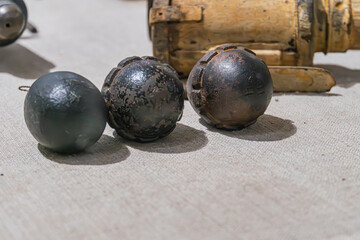 Three metallic grenades, varying in condition newer vs worn, arranged diagonally on a wood or metal...