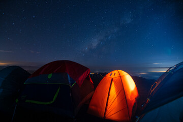 Orange camping tent illuminated inside during a blue starry night