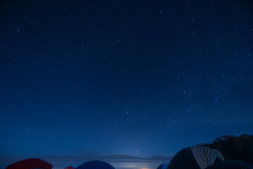 Cloudless blue starry night over a group of camping tents