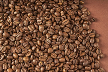 Coffee beans scattered on brown paper background