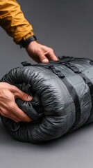 Hands rolling up a lightweight sleeping bag for outdoor adventure