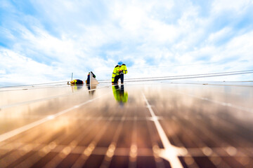 A solar energy engineer coordinates a project on the phone while on a rooftop solar installation. A...