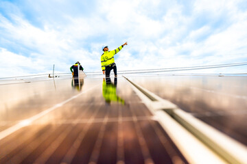A solar energy engineer coordinates a project on the phone while on a rooftop solar installation. A...
