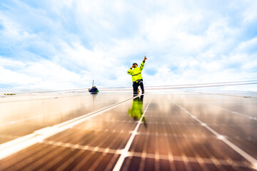 A solar energy engineer coordinates a project on the phone while on a rooftop solar installation. A...