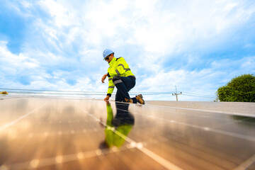 A technician in safety gear inspects solar panels on a metal rooftop, holding a tool. The scene...