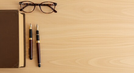 Brown book eyeglasses and fountain pens on beige wood table