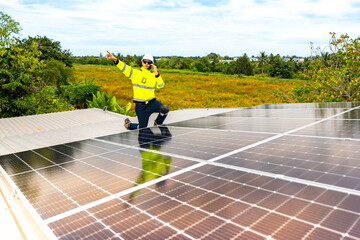 A confident engineer smiles and points at the camera while working on a rooftop solar panel...