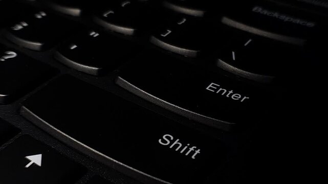 Close-up of a finger pressing the &lsquo;enter&rsquo; key on a laptop keyboard