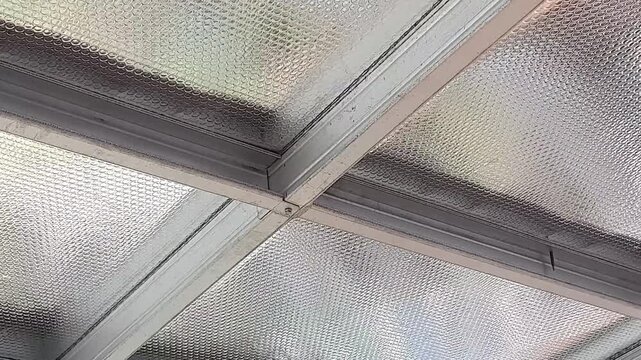 Close-up video panning across textured ceiling panels with metallic frames, featuring a repeating circular pattern, creating a modern architectural background.