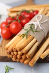 Delicious grissini sticks and rosemary on grey table, closeup